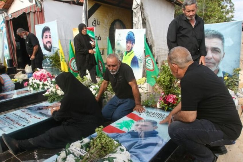 Relatives visit the graves of killed Hezbollah fighters during Eid al-Adha in the southern