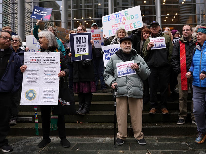 FILE - Martin Bernstein, 95, whose parents were refugees, at center, holds a sign as peopl