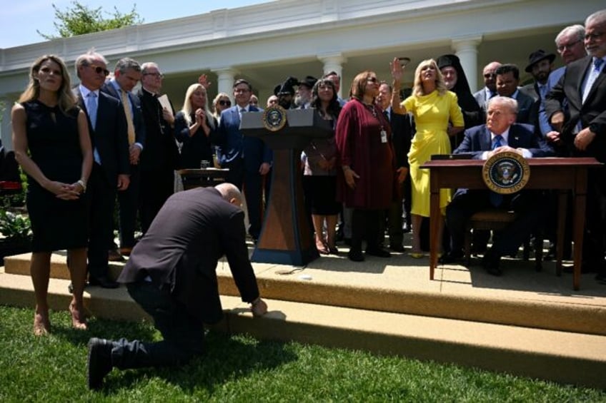 A man kneels in prayer in front of US President Donald Trump during a National Day of Pray