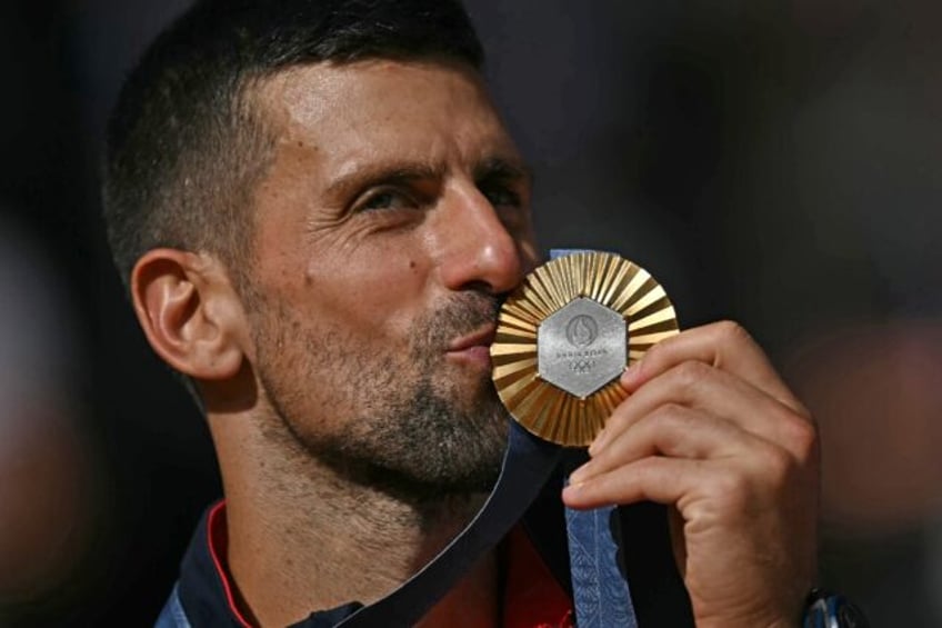 Novak Djokovic kisses his medal after winning his first Olympic title