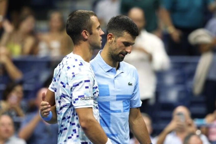 Painful end: Laslo Djere is consoled by Novak Djokovic after being forced to retire from