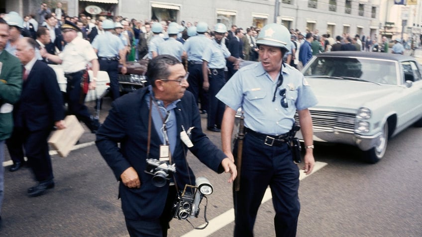 A police officer crossing the road with a photographer during an anti-war protest near the Democratic National Convention