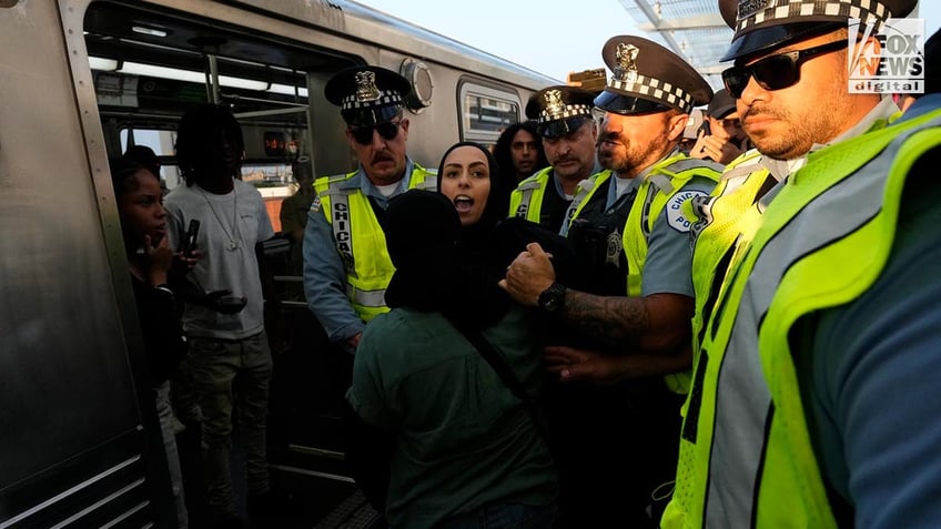 Police detain a woman outside of a train at a station