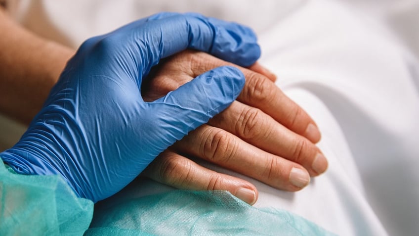 Health care worker holding patients hand