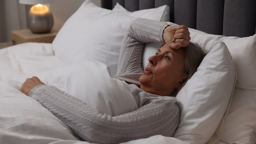 Woman suffering from hot flash in bed