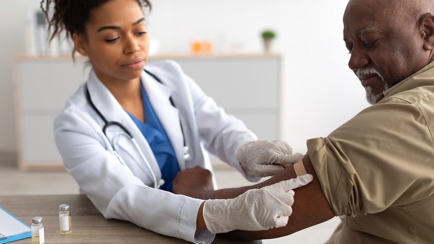 doctor applying adhesive to patients arm after injecting man