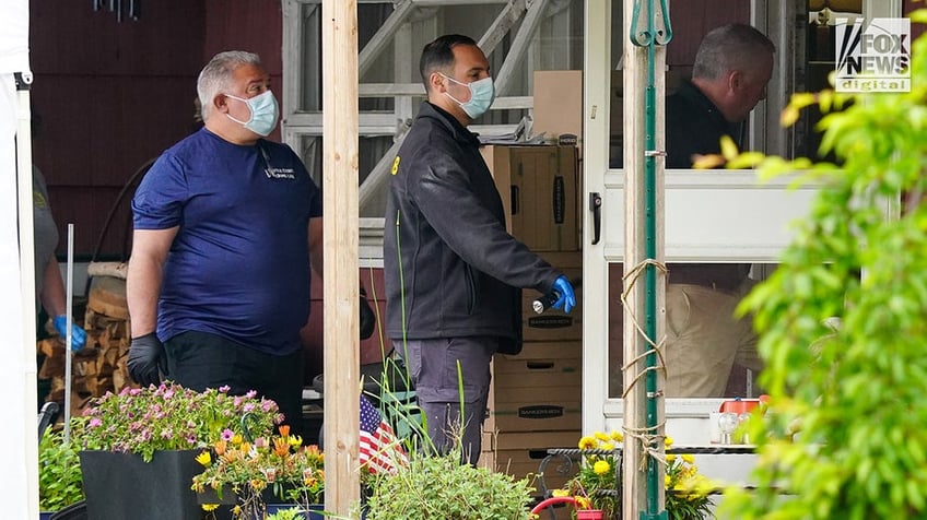 New York State and Suffolk County investigators remove bags of items marked with evidence tape from Rex Heuermann’s home in Massapequa Park