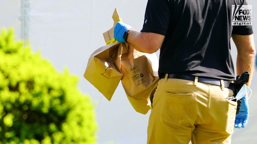 New York State and Suffolk County investigators remove bags of items marked with evidence tape from Rex Heuermann’s home in Massapequa Park