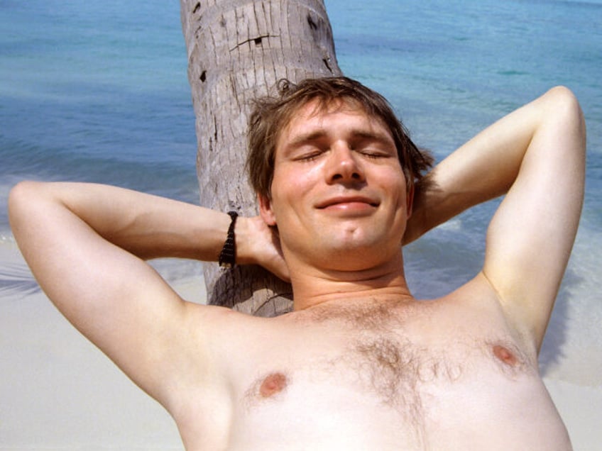 young man dozing on palm tree by the sea