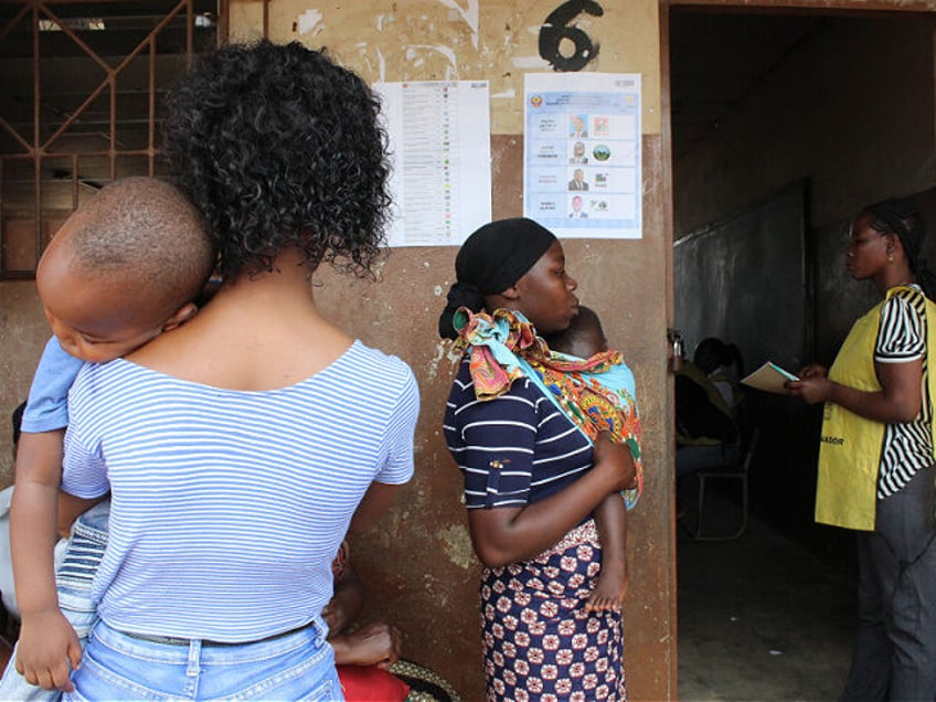 Mothers holding their babies queue to cast their votes at Polana Canic?o Primary School in