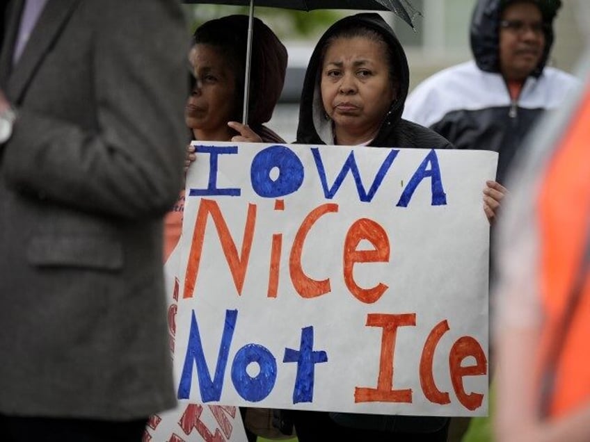 A woman listens to a speaker during an Iowa Movement for Migrant Justice rally and march,