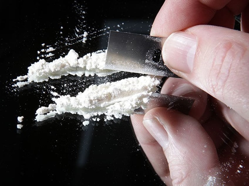 cocaine or other drugs cut with razor blade on mirror. hand dividing white powder narcotic