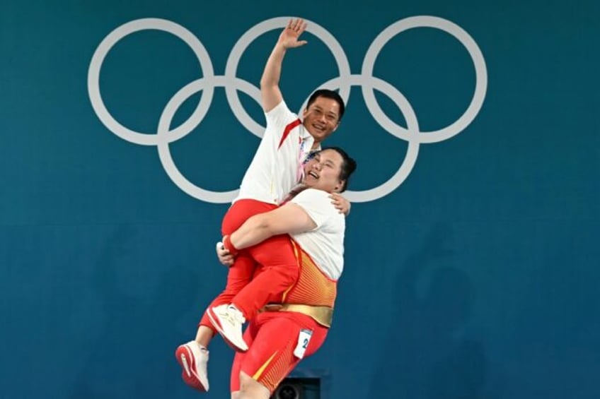 China's Li Wenwen hoists her coach Wu Meijin aloft after winning women's +81kg weightlifti