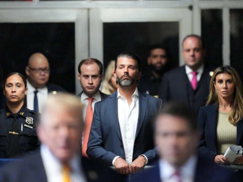 Donald Trump Jr. listens as his father former President Donald Trump speaks to the media a