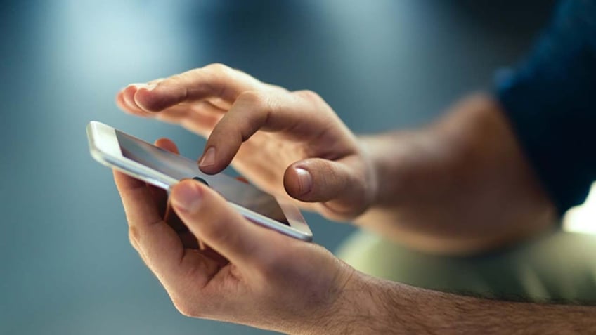 Man holds smartphone and touches screen