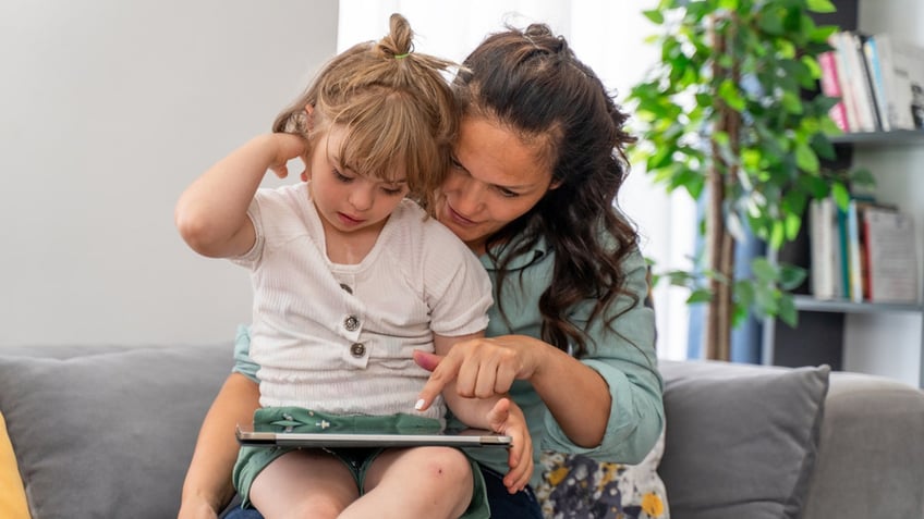 parent and child with down syndrome on tablet