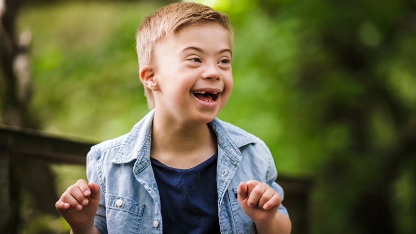 little boy with down syndrome playing in a park