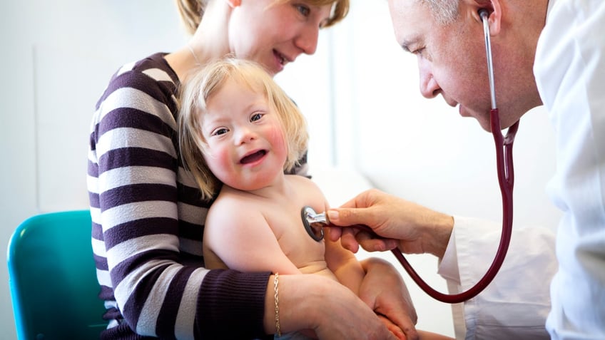 doctor checks the heartbeat of down syndrome child