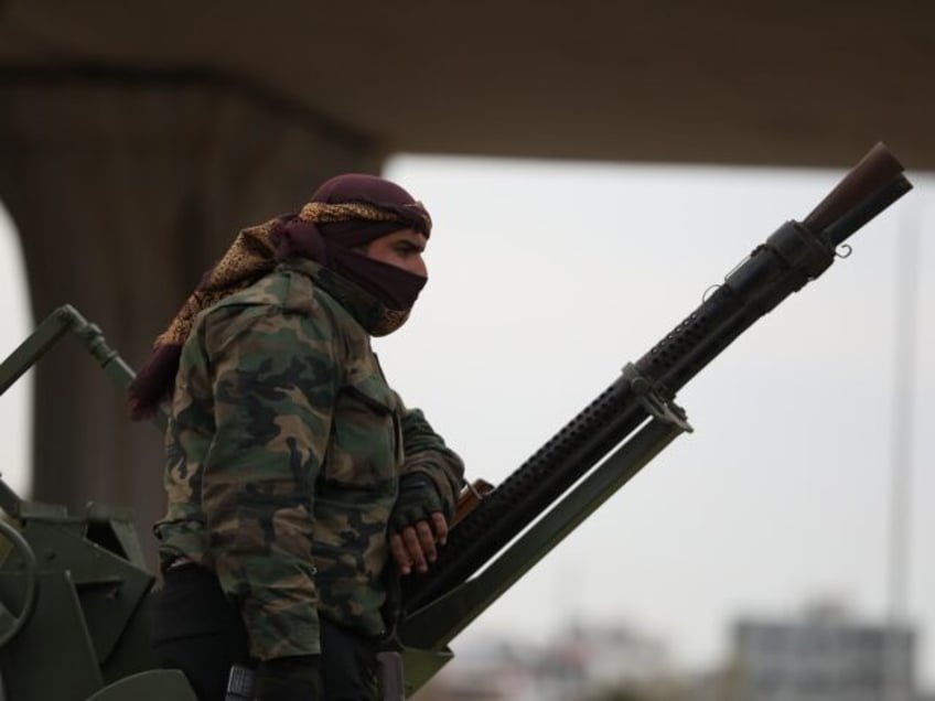 TARTUS, SYRIA - MARCH 7: A fighter with the new Syrian government stands next to an anti-a