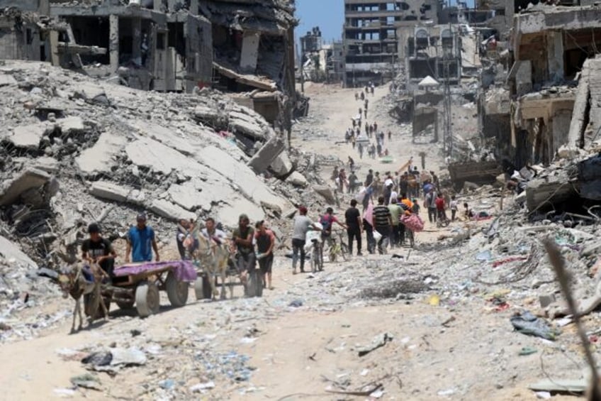 Palestinians walk past destroyed buildings in Gaza City's Shujaiya neighbourhood after the