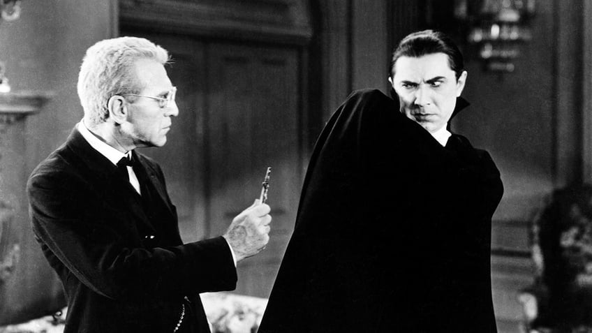 Bela Lugosi leaning away from a priest holding a cross as Dracula.