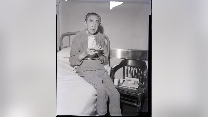 Bela Lugosi sitting on a hospital bed