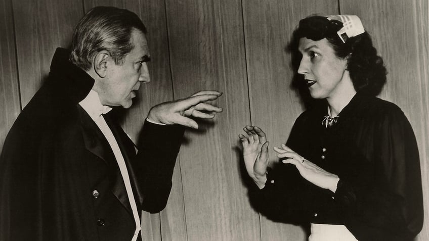 Bela Lugosi in costume scaring his wife Lillian on stage.