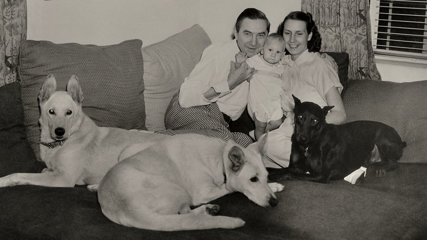 Bela Lugosi and his wife Lillian holding onto their son surrounded by dogs