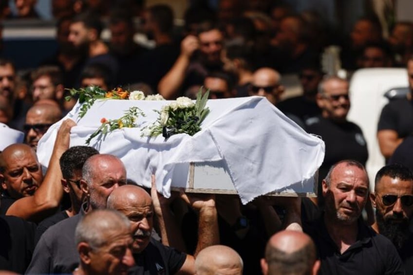 Druze pallbearers carry the coffin of Guevara Ibrahim, 11, one of 12 children killed in a