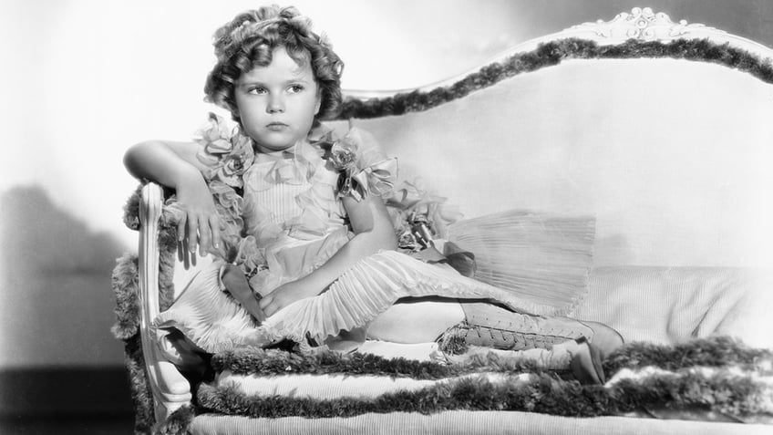 Shirley Temple in 1935 sitting on a couch.