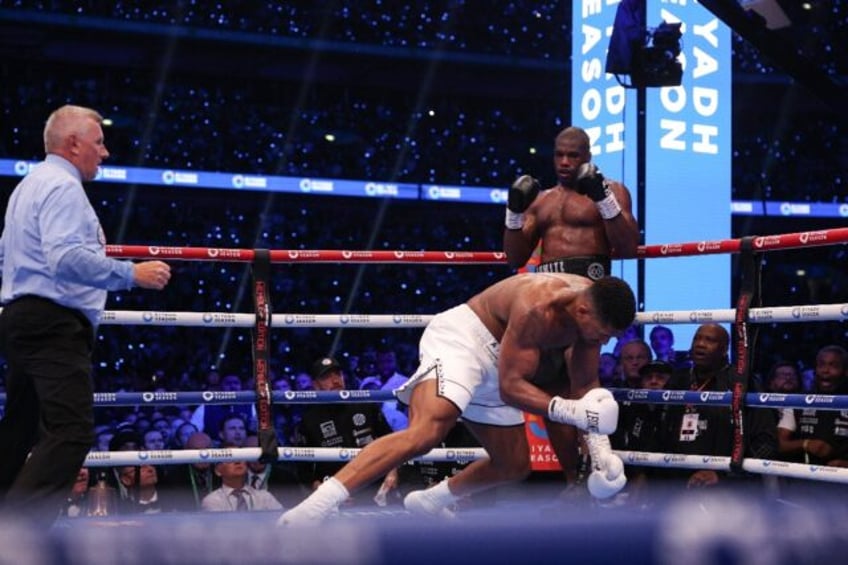 Anthony Joshua is knocked to the ground by Daniel Dubois during their IBF world title figh