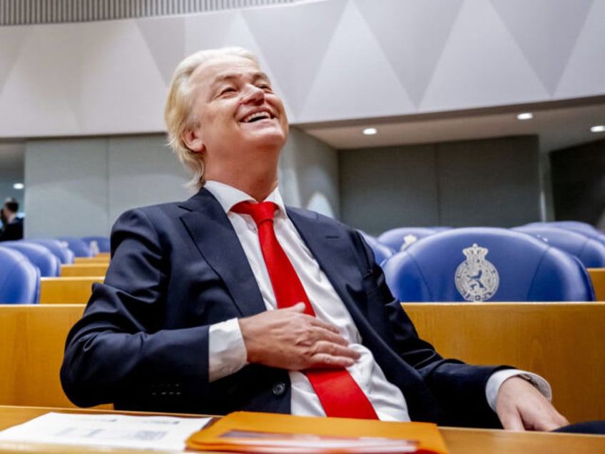 Dutch far-right PVV party leader Geert Wilders (R) reacts ahead of a debate at the House o