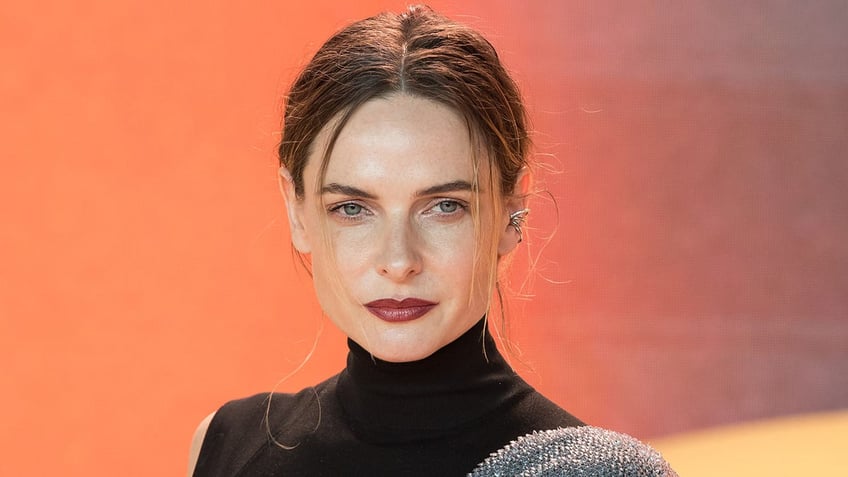 Rebecca Ferguson looks serious on the carpet in a black gown with a silver spiked shoulder