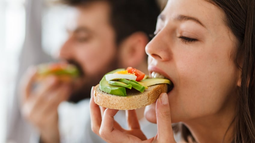 woman bites into avocado toast