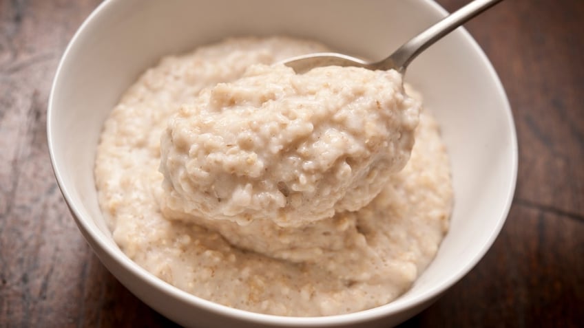 A spoonful of oatmeal emerges from a white bowl.