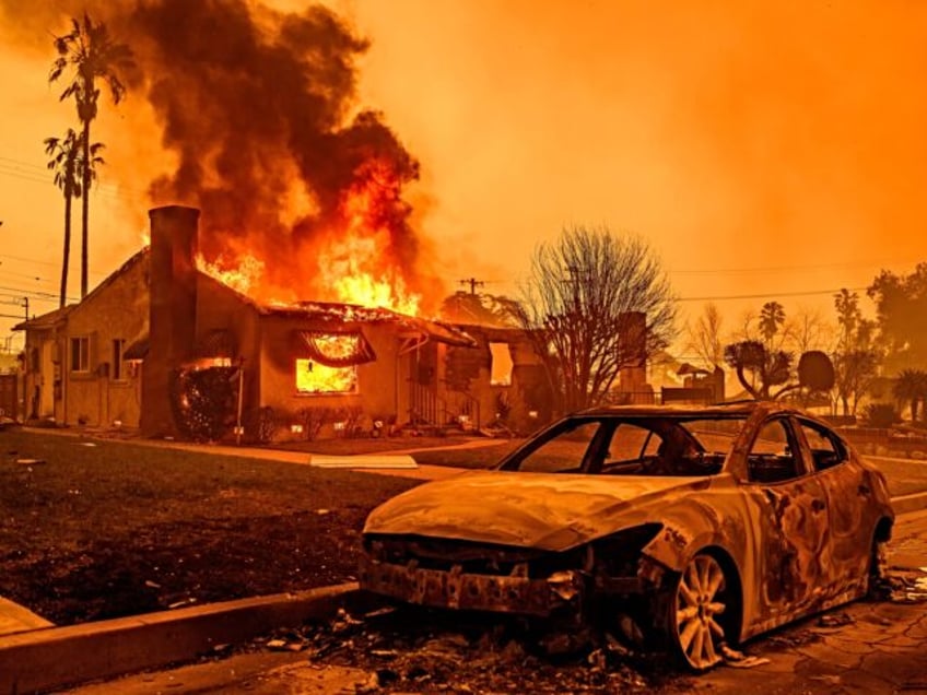 The carcass of a burnt-out car is seen as home burns during the Eaton fire in the Altadena