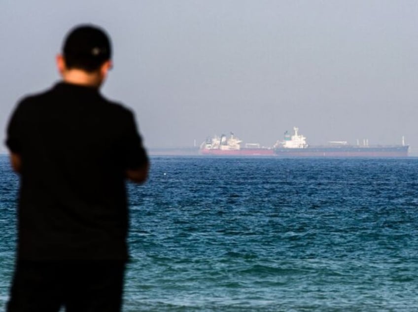 A man stands along a beach as tanker ships are seen in the waters of the Gulf of Oman off the coast of the eastern UAE emirate of Fujairah on June 15, 2019. (Photo by GIUSEPPE CACACE / AFP) (Photo credit should read GIUSEPPE CACACE/AFP via Getty Images)