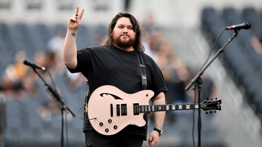 Wolfgang Van Halen flashing a peace sign on stage