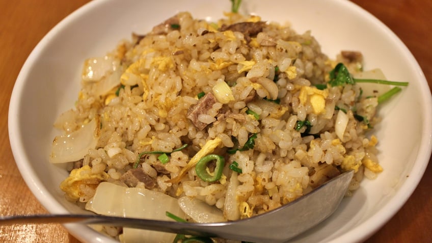 A spoon rests in a bowl of fried rice.