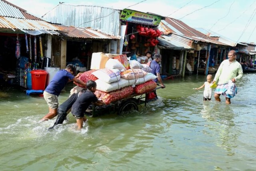 People push a handcart carrying supplies through the flood at Fenchuganj in Sylhet on July