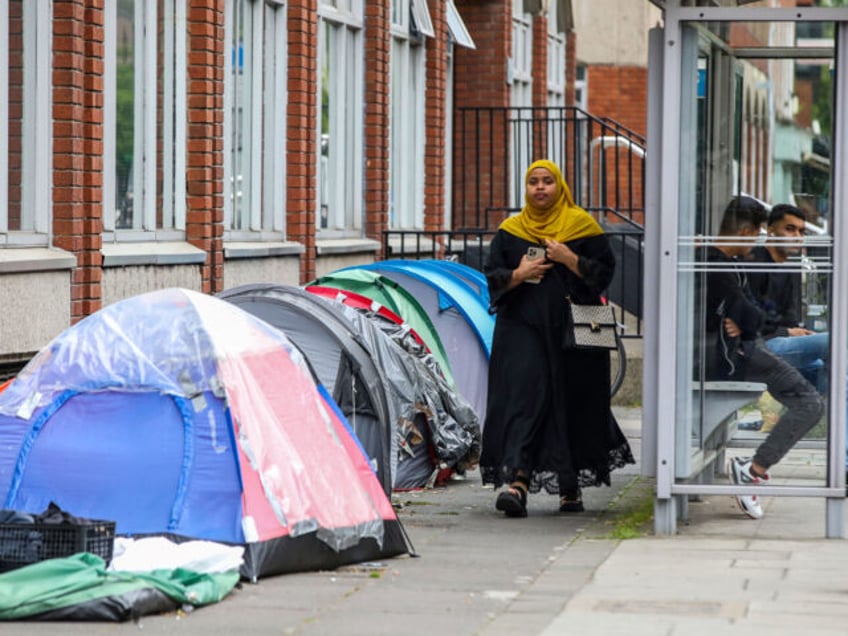 A woman walks past tents at a makeshift refugee camp outside the Irish Governments Interna