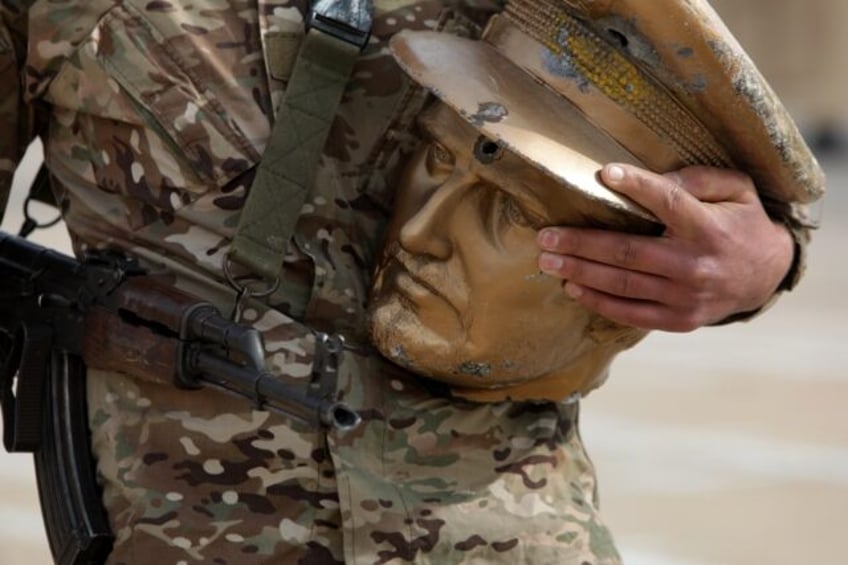 A fighter affiliated with Syria's new administration carries the decapitated head of an eq