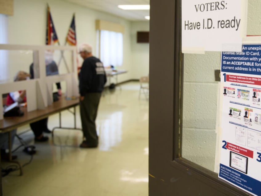 A voter shows identification to an election judge during primary voting on May 3, 2022 in