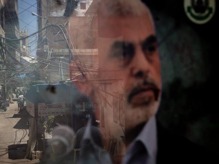 People are reflected in a window displaying a poster of newly appointed Hamas leader Yahya