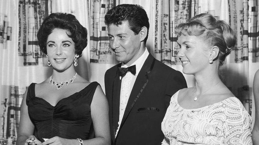 Eddie Fisher standing in between Elizabeth Taylor and Debbie Reynolds.