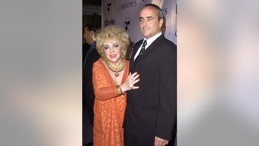 Elizabeth Taylor in an orange dress holding onto her son Christopher Wilding.