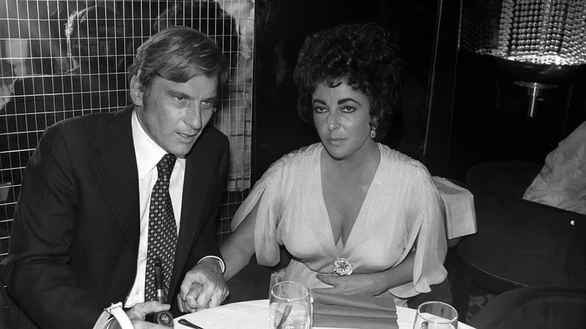 Elizabeth Taylor sitting with John Warner looking glum.