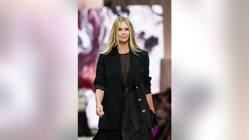 Elle MacPherson walks the runway in a sheer black top with a black blazer