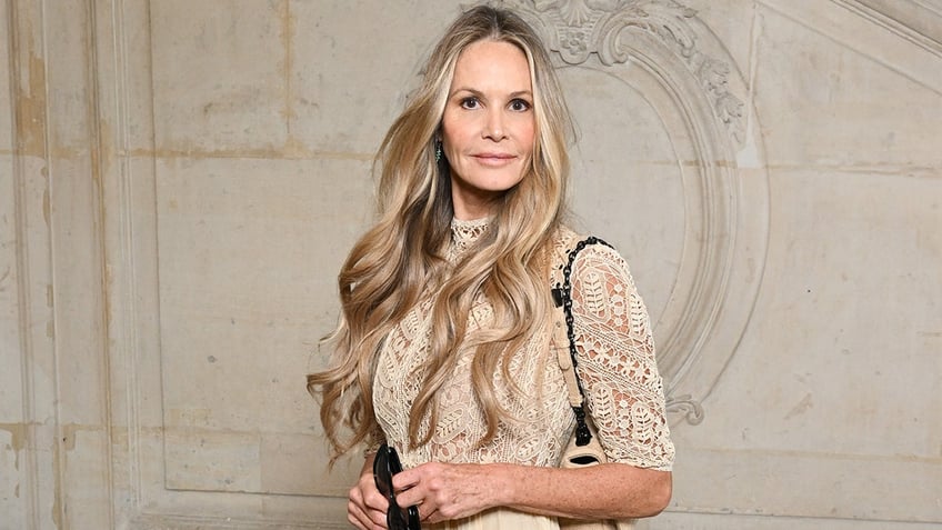 Elle Macpherson in a lace white top stares directly at the camera