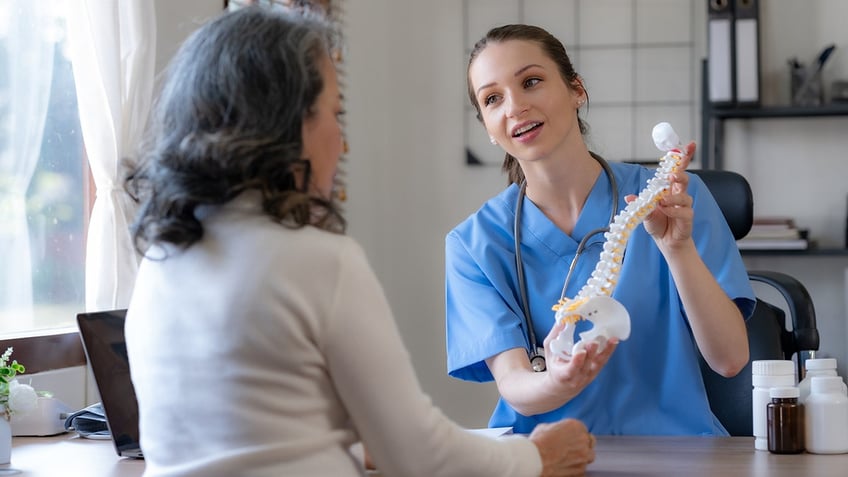 doctor shows female patient model of a human spine